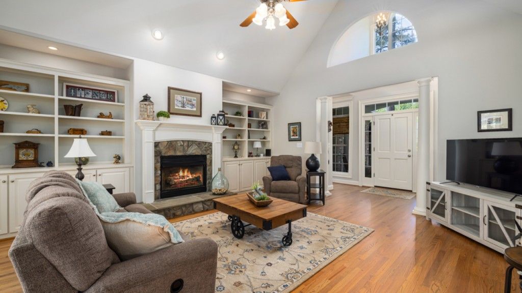 Living room with fireplace, built-in shelves, and large windows