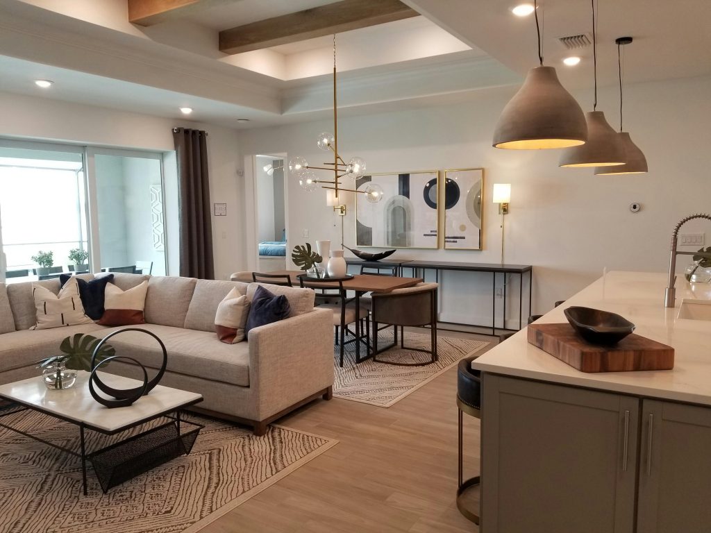 Modern open living area with neutral sectional sofa, chic decor, pendant lighting, and a stylish dining and kitchen space.