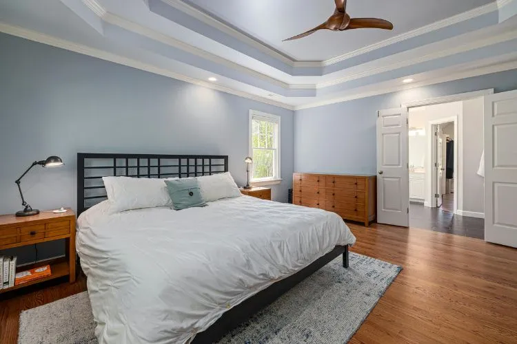 spacious bedroom with a modern design features a large bed, wooden furniture, soft lighting, and an open doorway