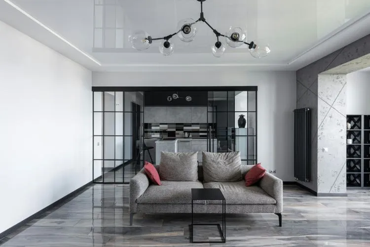 modern living room with a sleek gray sofa, accented by red pillows, sits in front of a stylish open kitchen