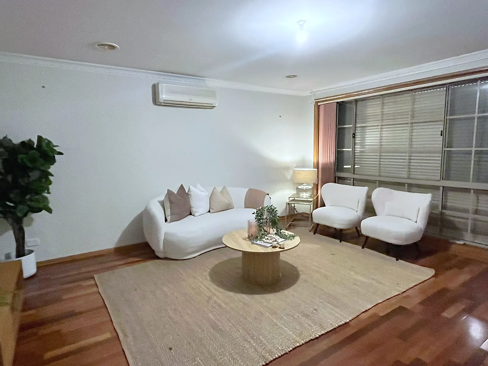 Lounge staged with curved sofa and jute rug on timber floors in an Altona Meadows home