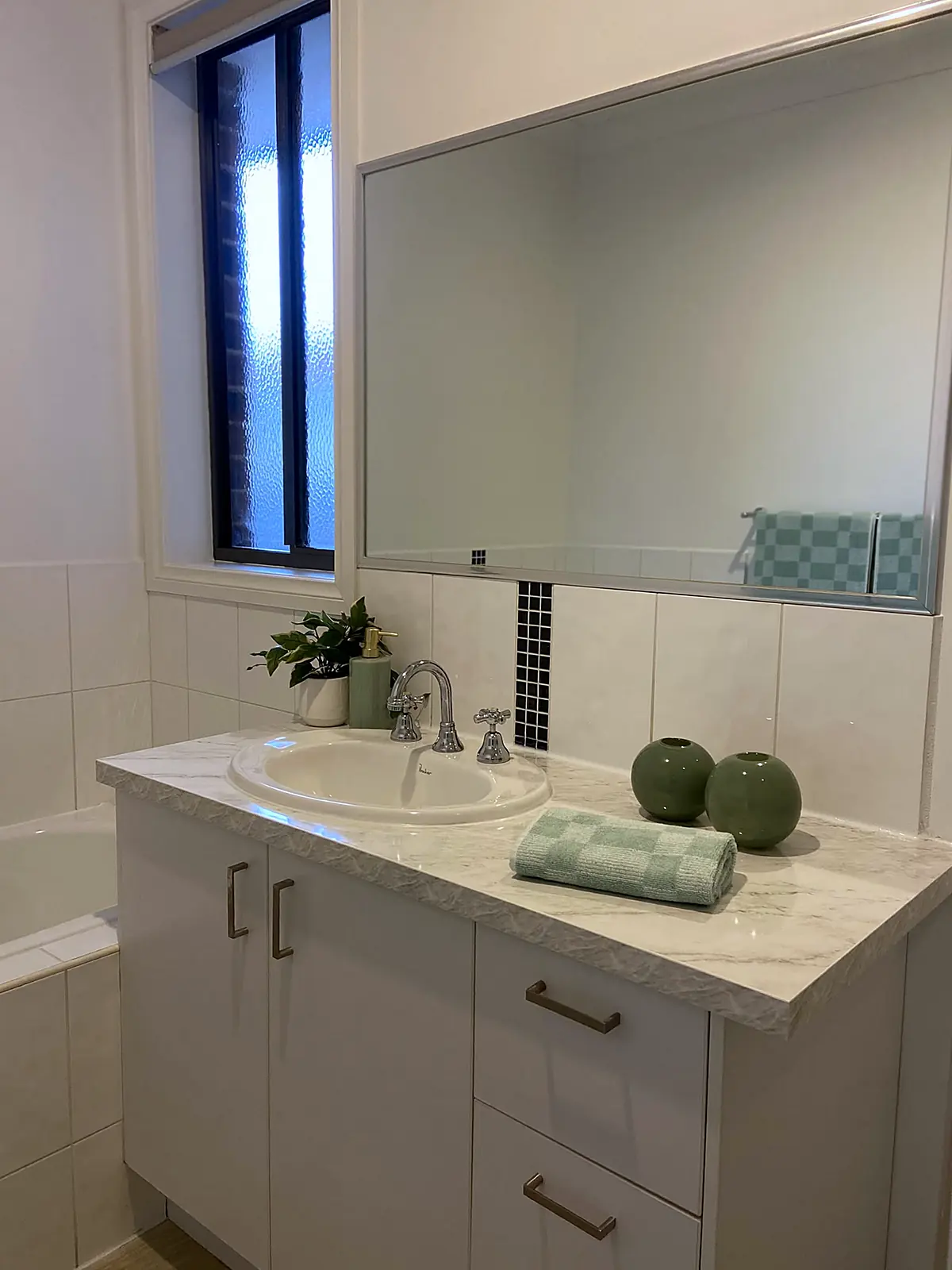 Bathroom vanity styled with towels and greenery in an Altona North unit