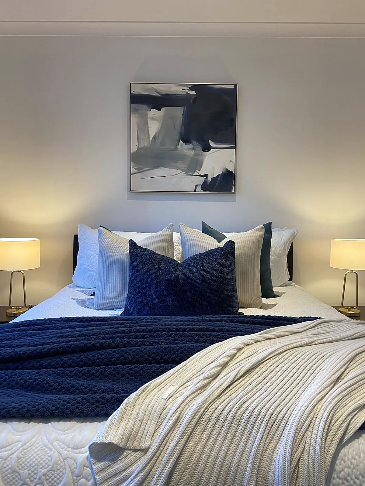 Main bedroom staged with navy cushions and abstract artwork in an Altona North unit