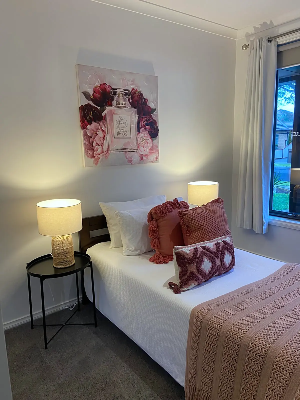 Bedroom staged with rose throw and red cushions in an Altona North unit