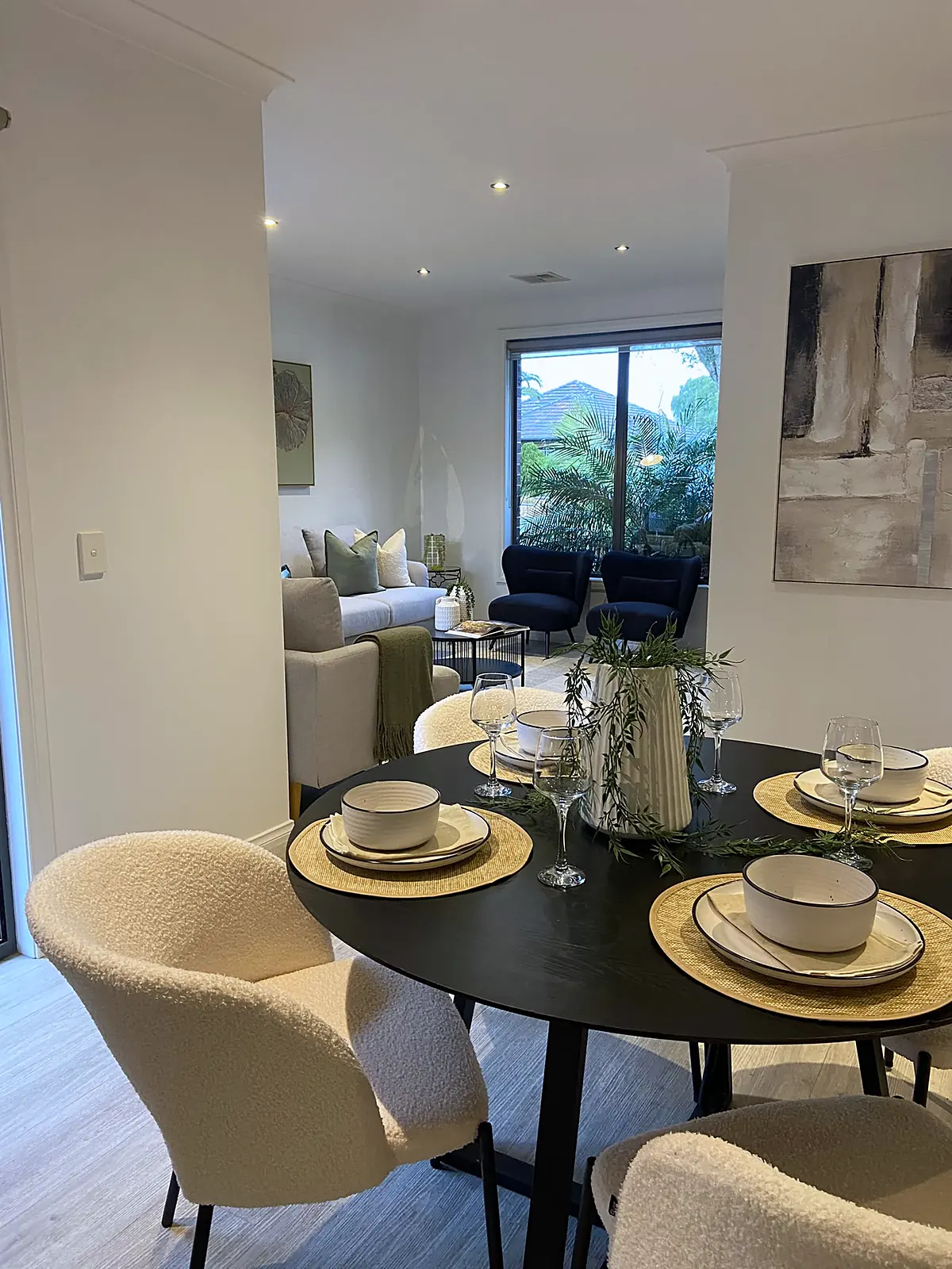 Round black dining table with boucle chairs in a staged Altona North unit