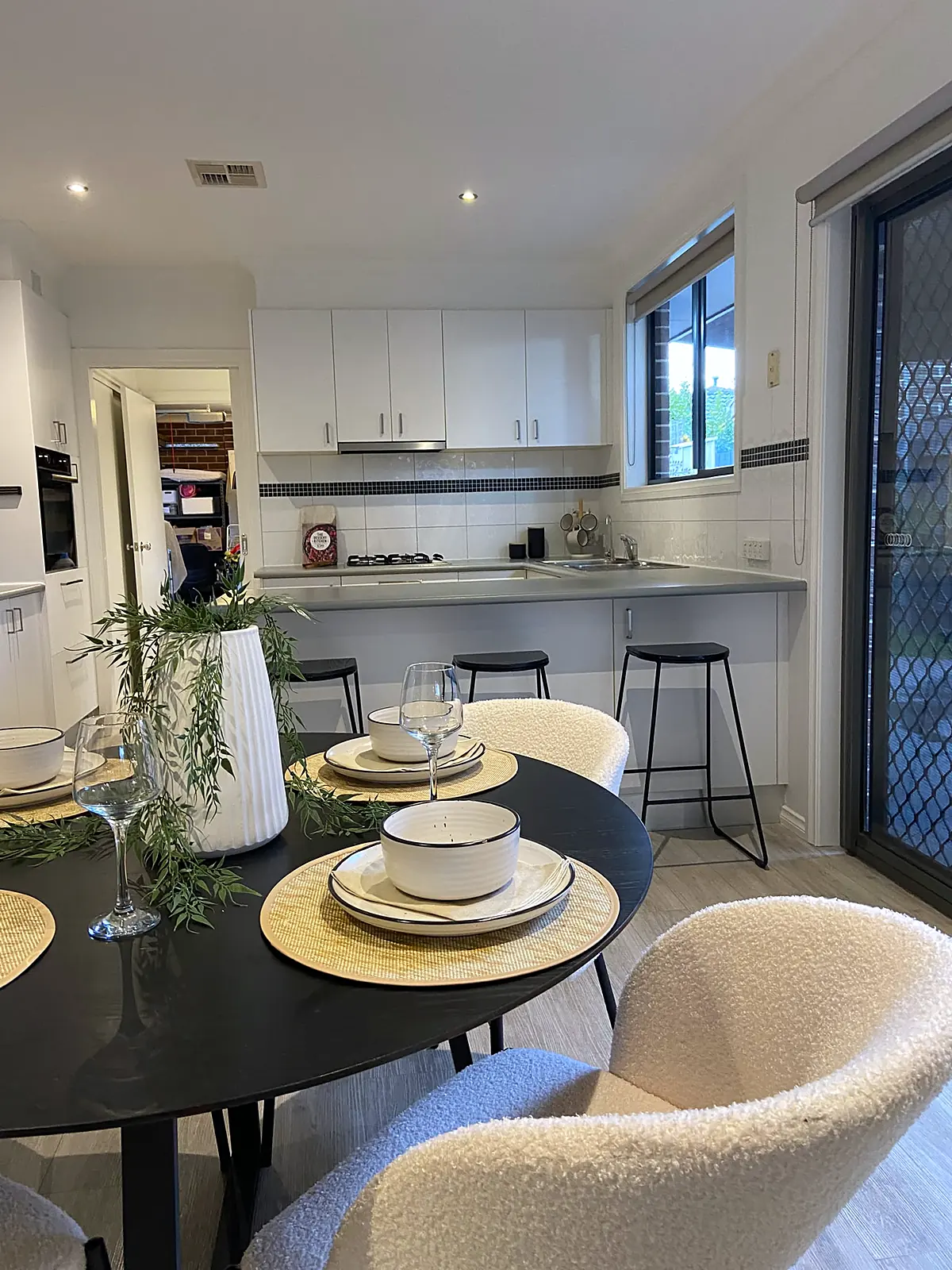 Dining table set beside the kitchen in a staged Altona North unit