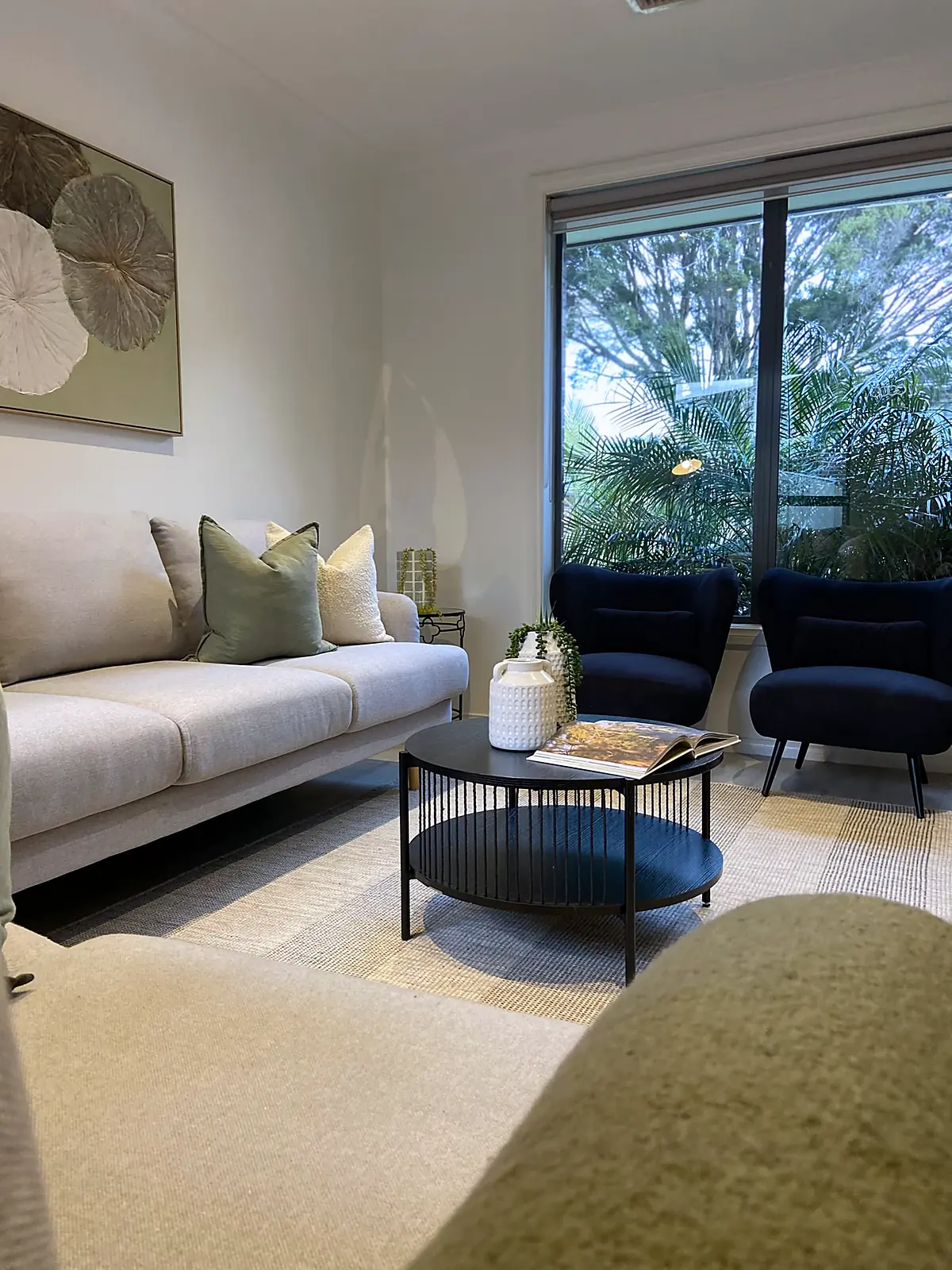 Living room staged with grey sofa and navy armchairs in an Altona North unit