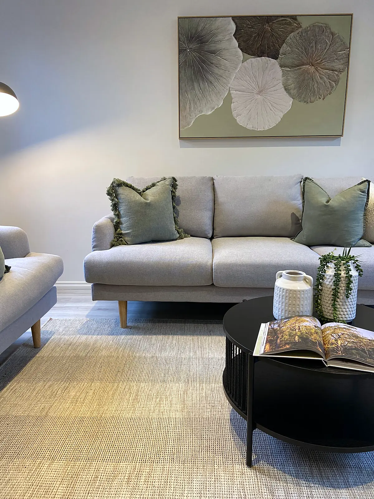Sofa with sage cushions and botanical artwork in a staged Altona North living room