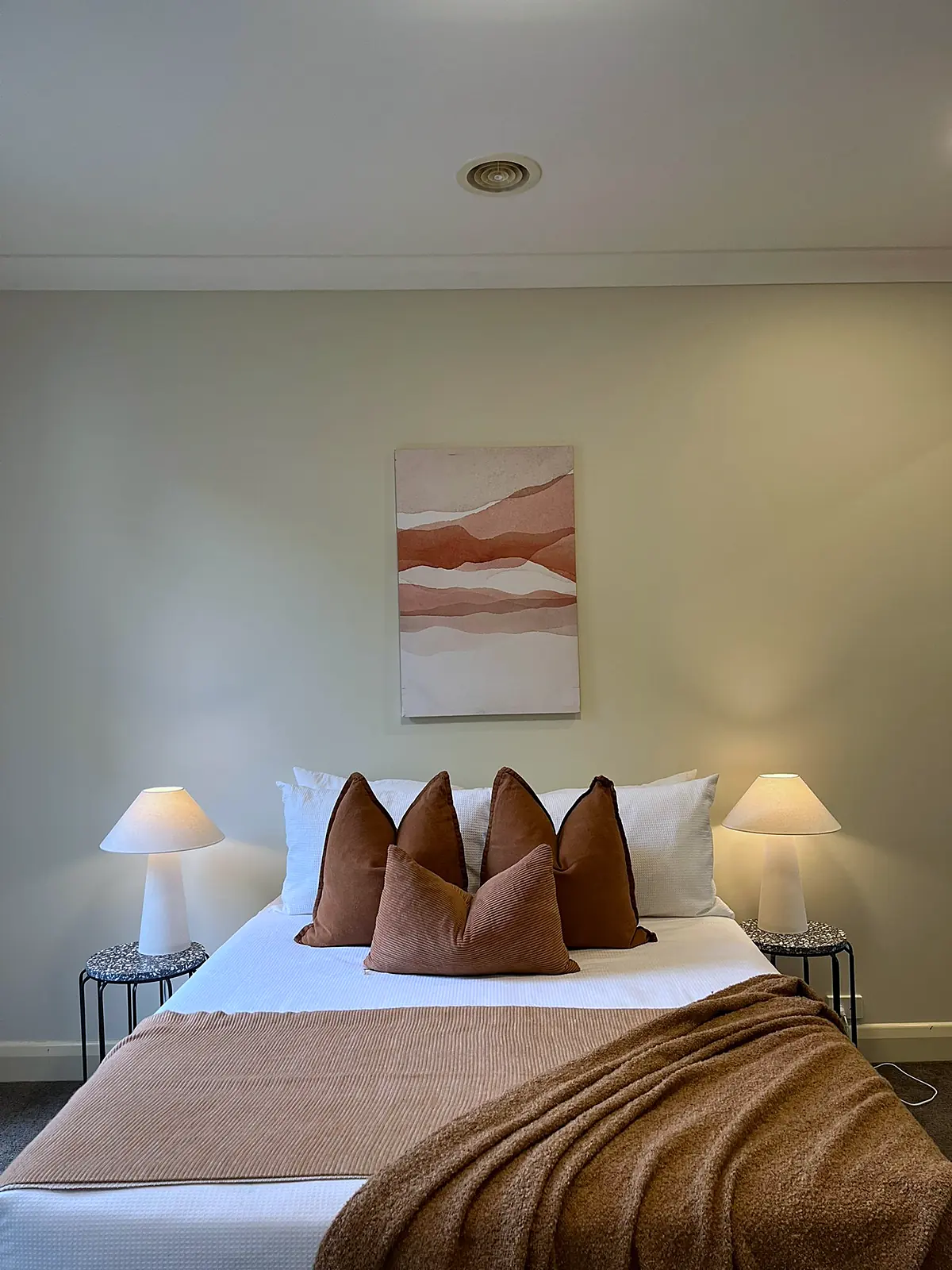 Bedroom styled with rust cushions and throw in a Balwyn home