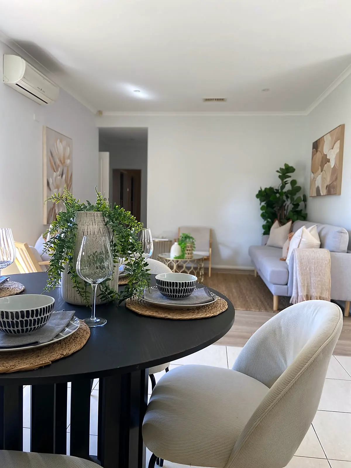 Round black dining table set with the lounge beyond in a staged Braybrook home