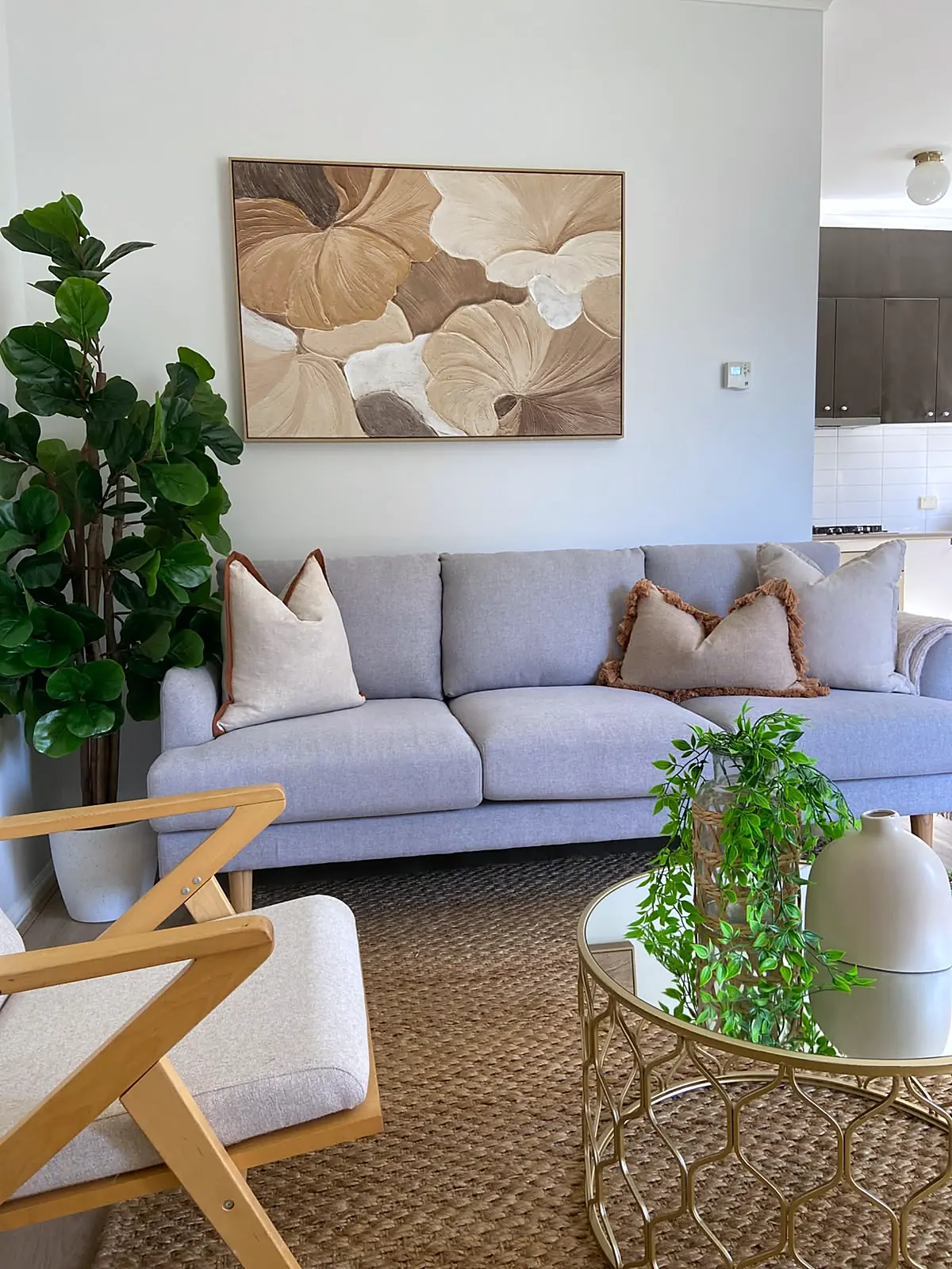 Lounge staged with grey sofa, timber armchairs and botanical artwork in a Braybrook home