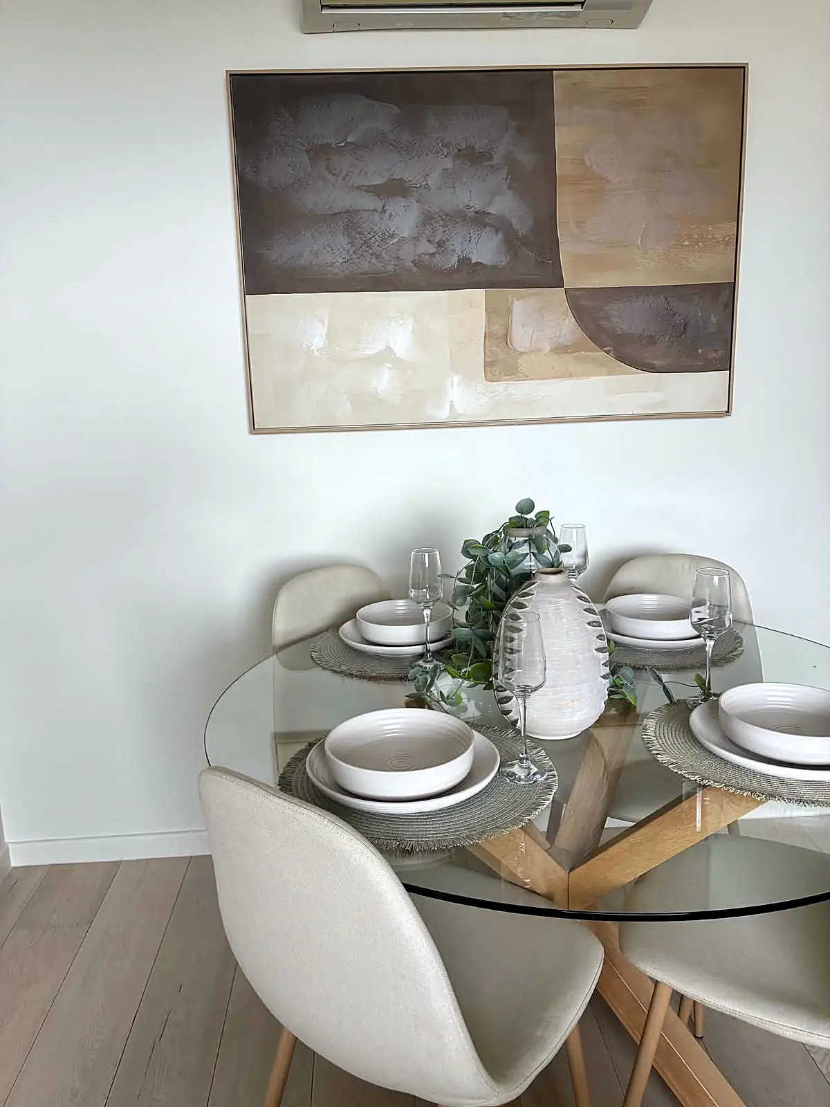 Round glass dining table with boucle chairs and artwork in a Brunswick apartment