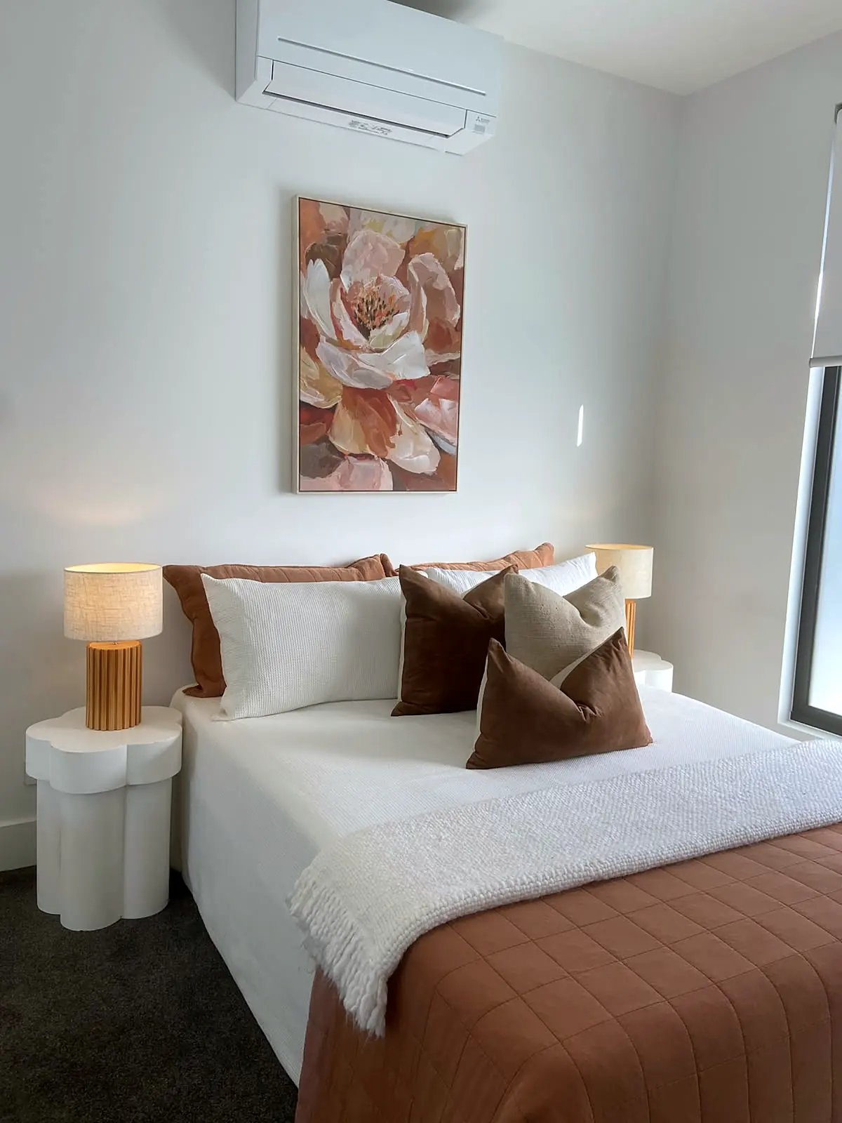 Bedroom styled with rust throw and floral artwork in a Bulleen home