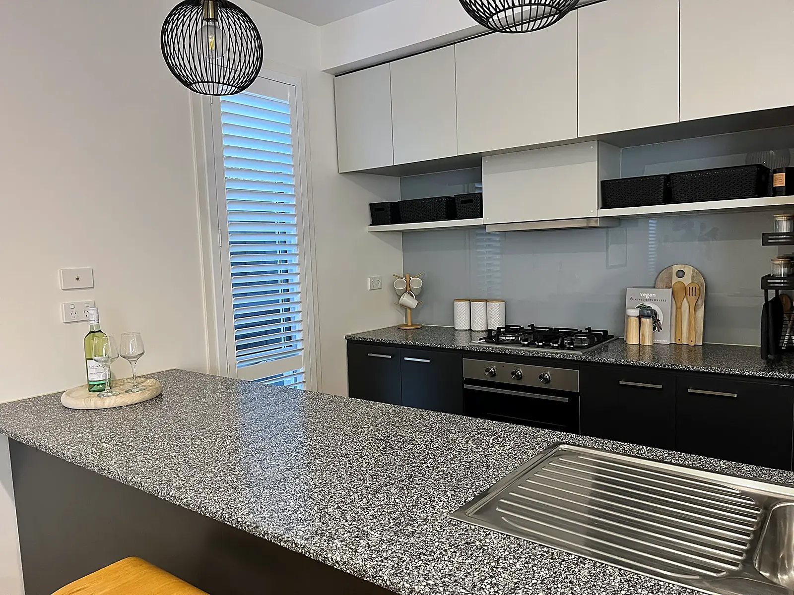 Black kitchen with stone benchtop styled for sale in a Bundoora home