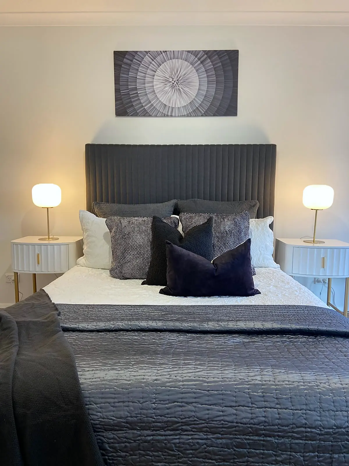 Main bedroom staged with charcoal bedhead and navy cushions in a Burnside Heights home