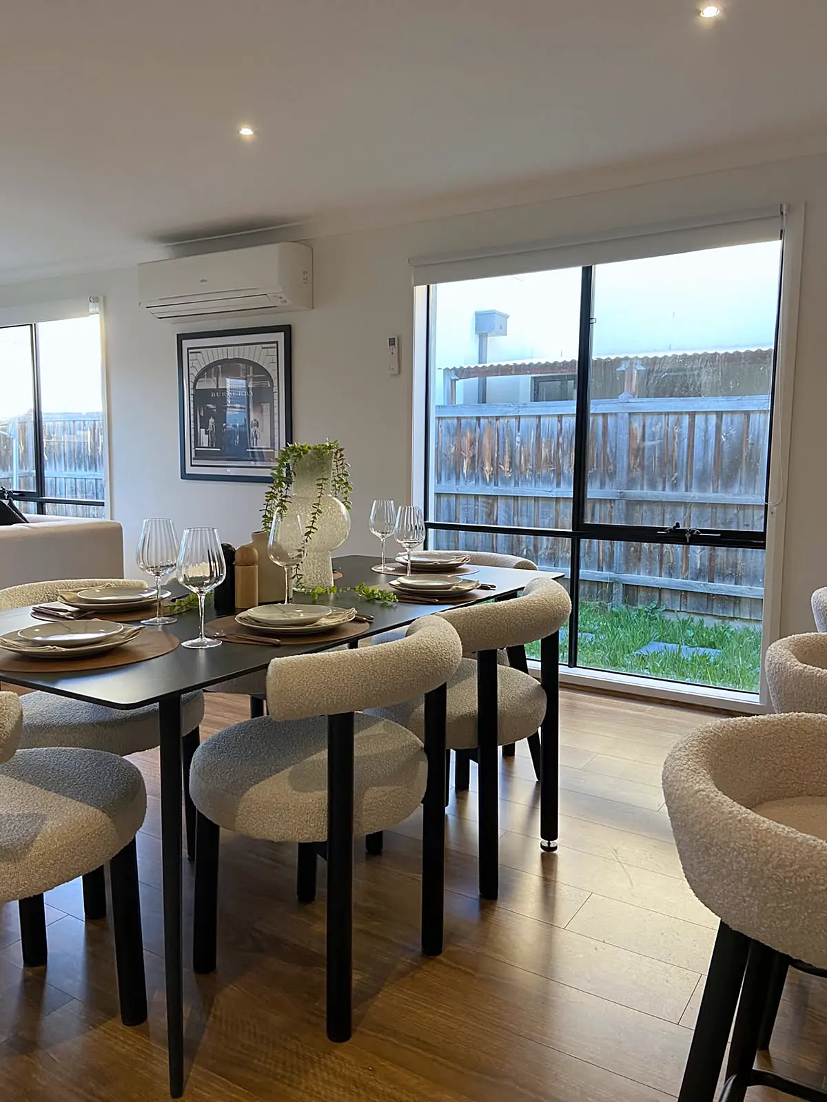 Dining table with boucle chairs beside the windows in a staged Burnside Heights home