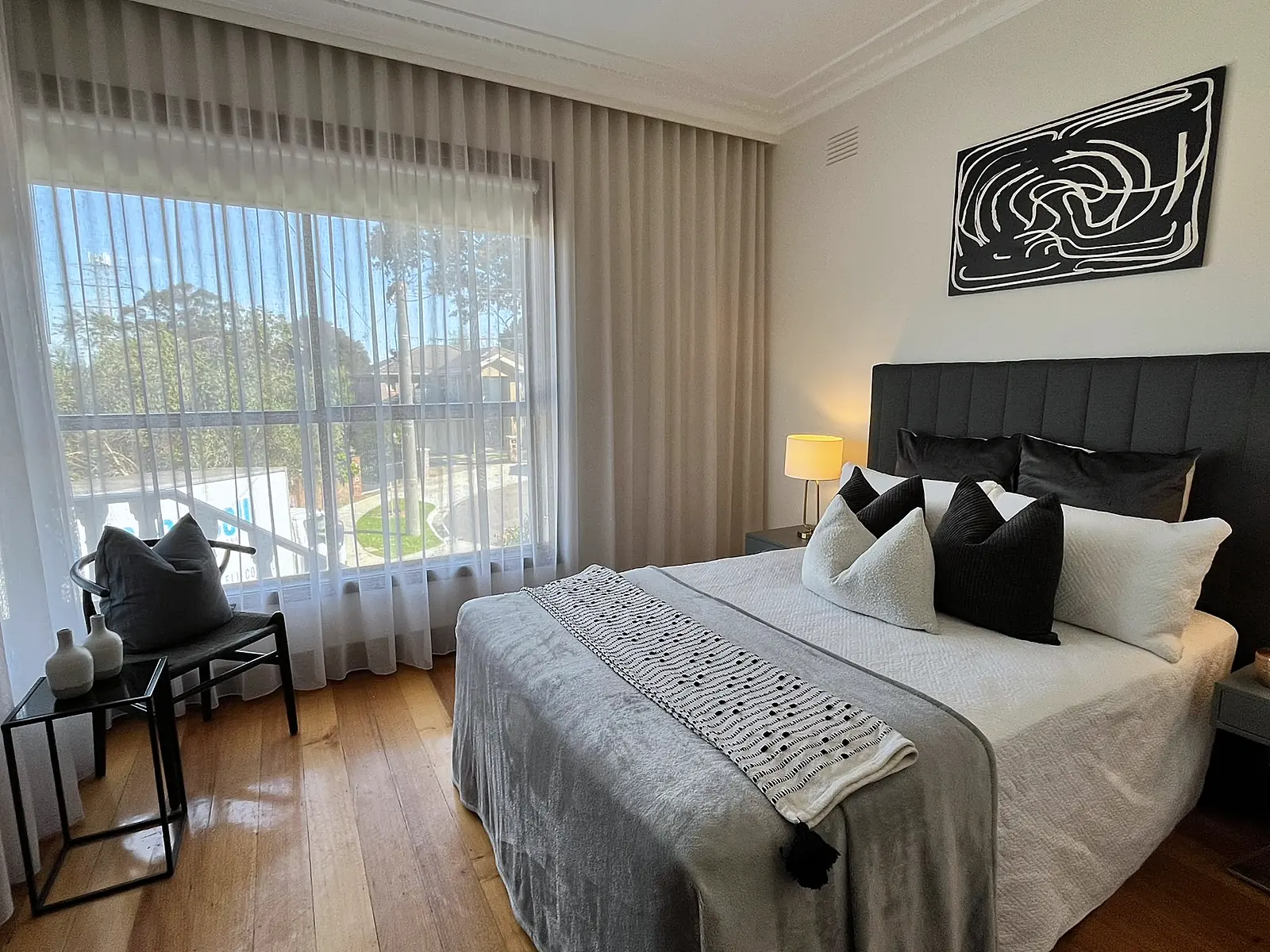 Bedroom with leafy outlook staged with dark bedhead in a Chadstone home