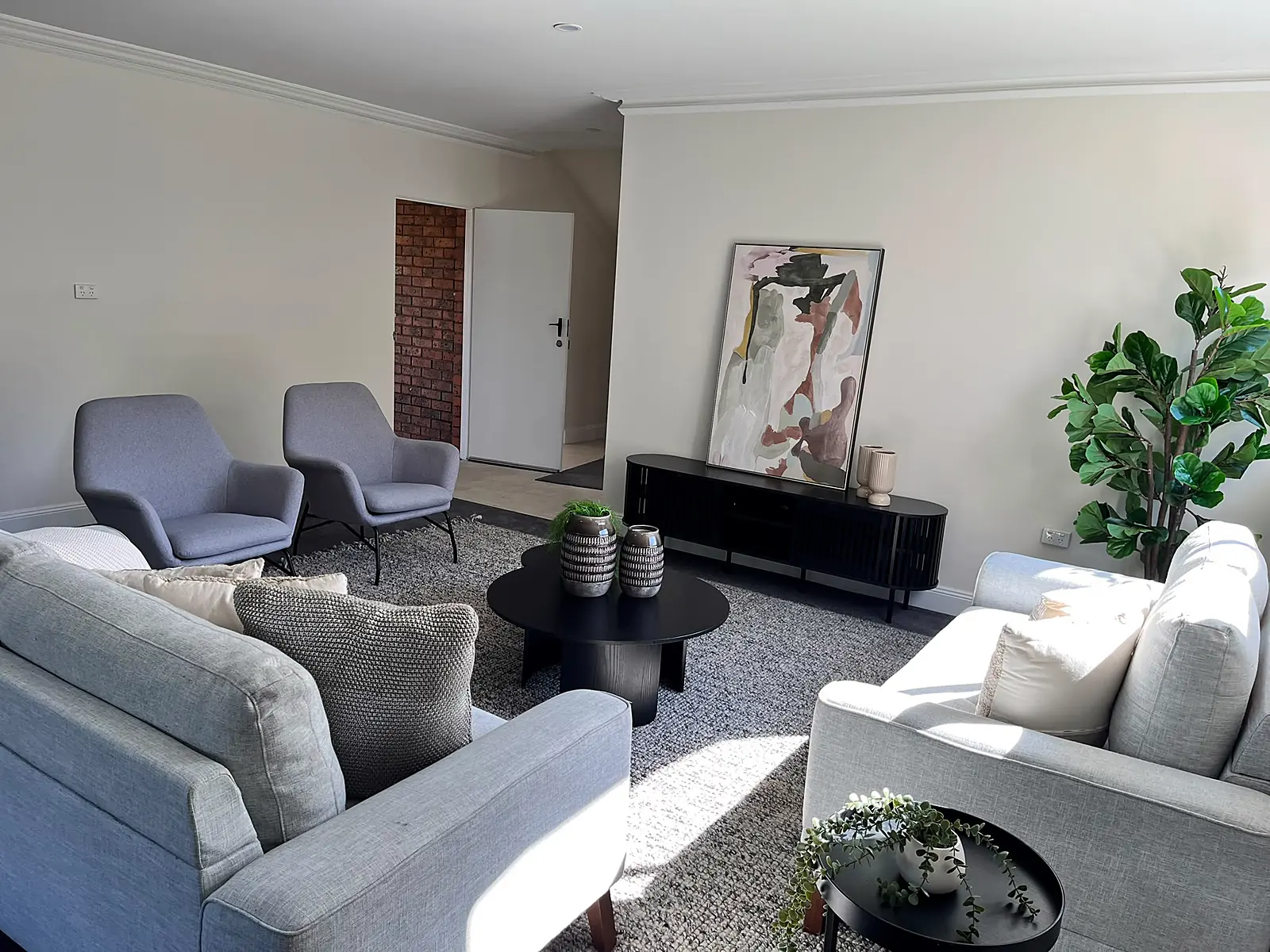 Family room staged with sofas, armchairs and rug in a Chadstone home