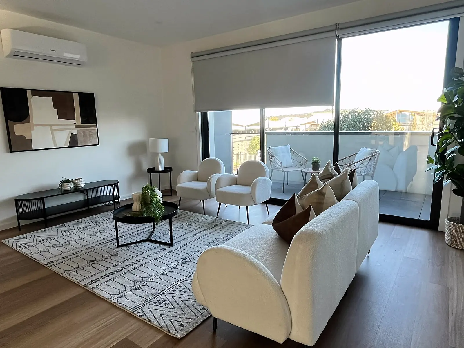 Staged living room with curved sofa and balcony access in a Craigieburn home