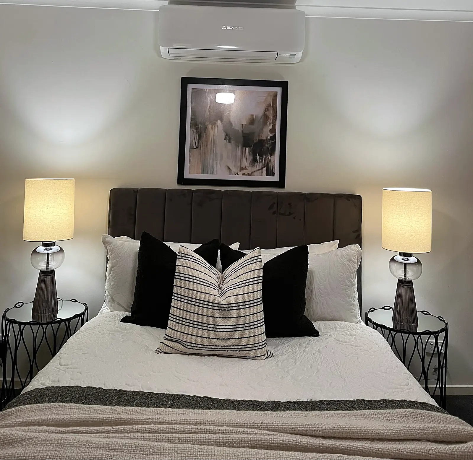 Main bedroom staged with dark bedhead and striped cushion in a Deer Park home