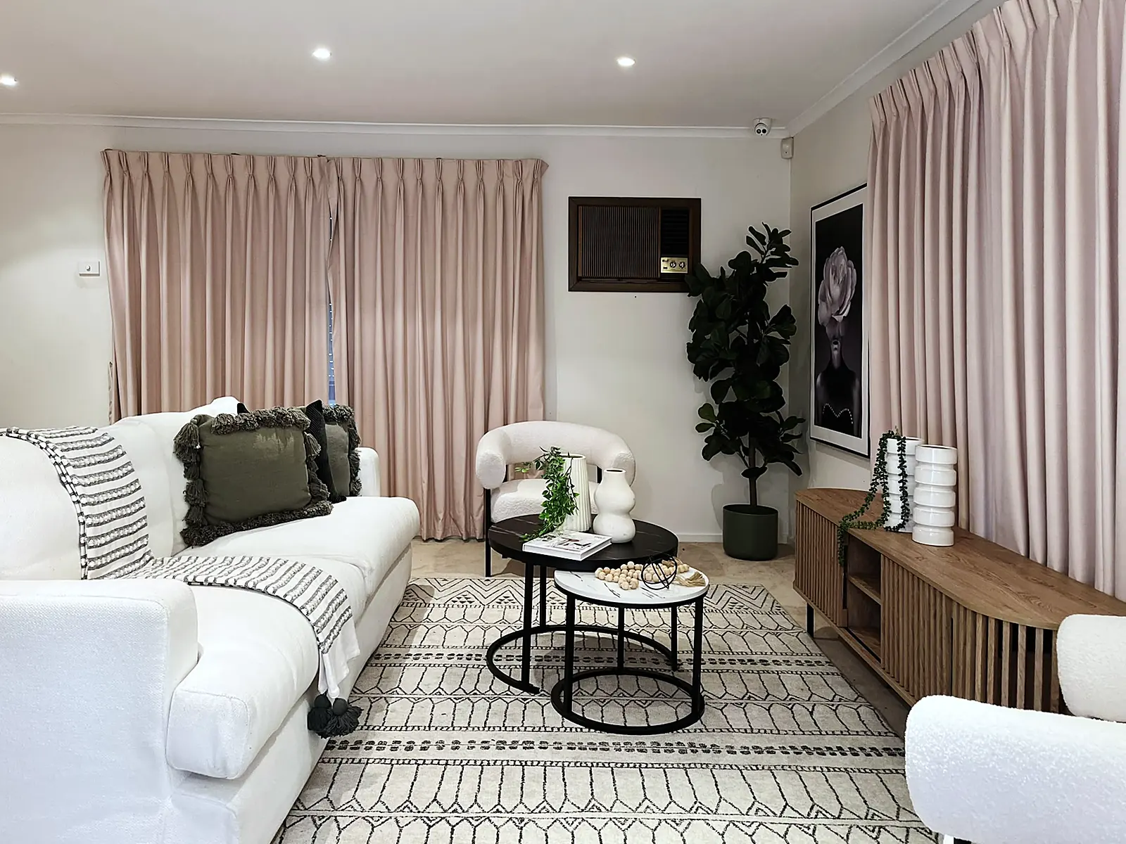 Lounge with pink curtains staged with white sofas and patterned rug in a Deer Park home