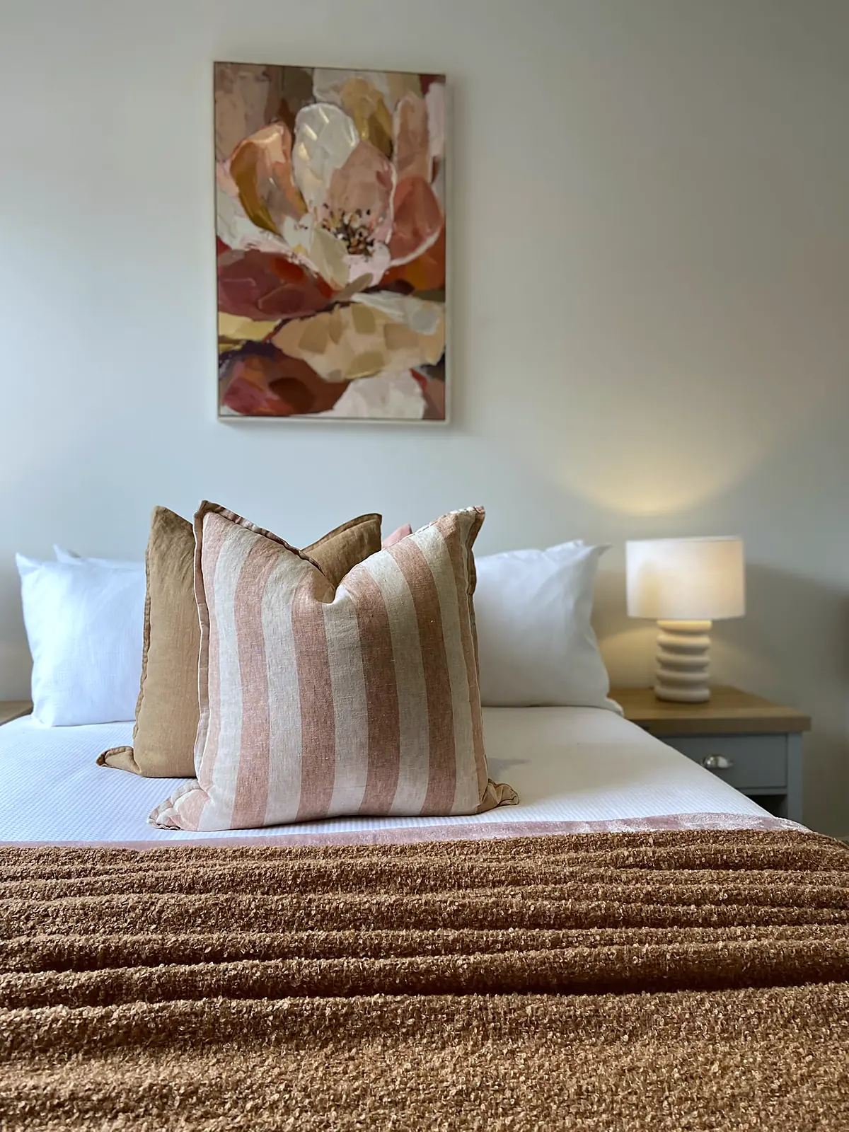 Bedroom styled with rust throw and floral artwork in a Diggers Rest home