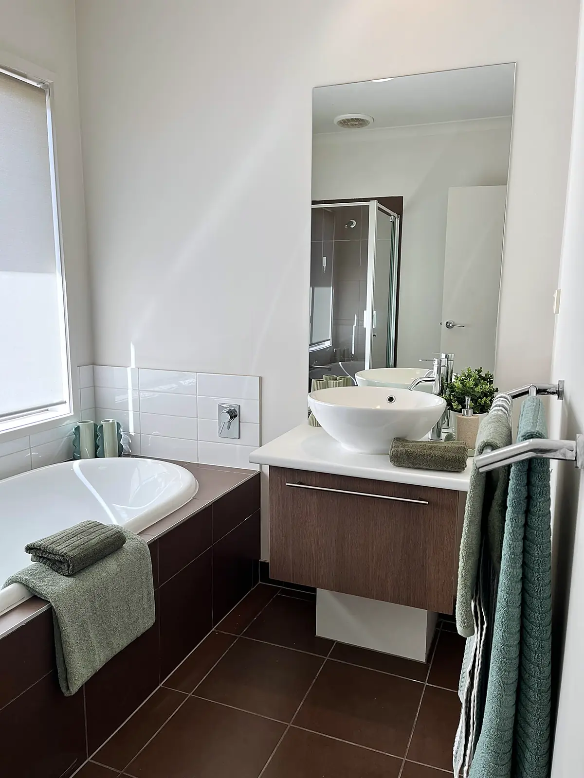 Bathroom with bath styled with green towels in a Doreen home