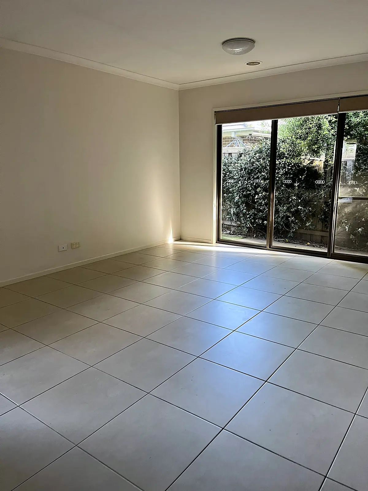 Empty tiled living room with garden outlook before staging in a Doreen home