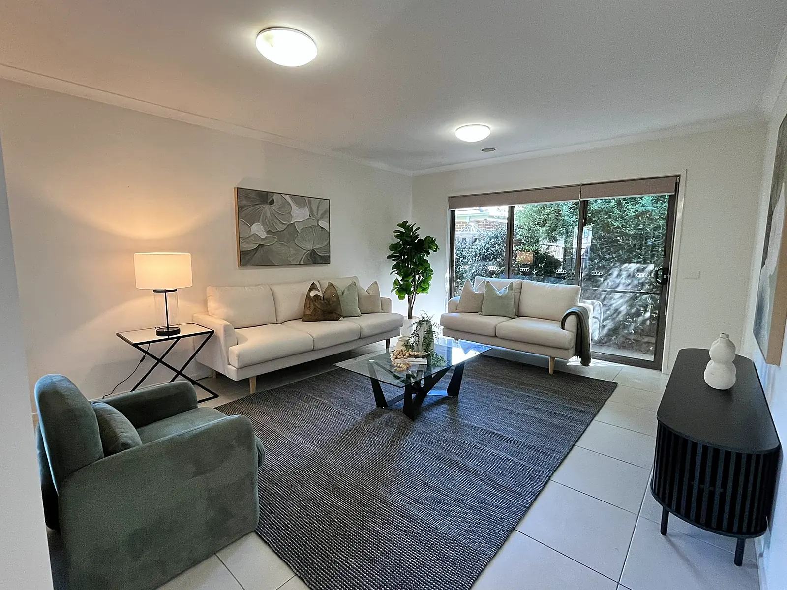 Living room staged with cream sofas and green armchair in a Doreen home