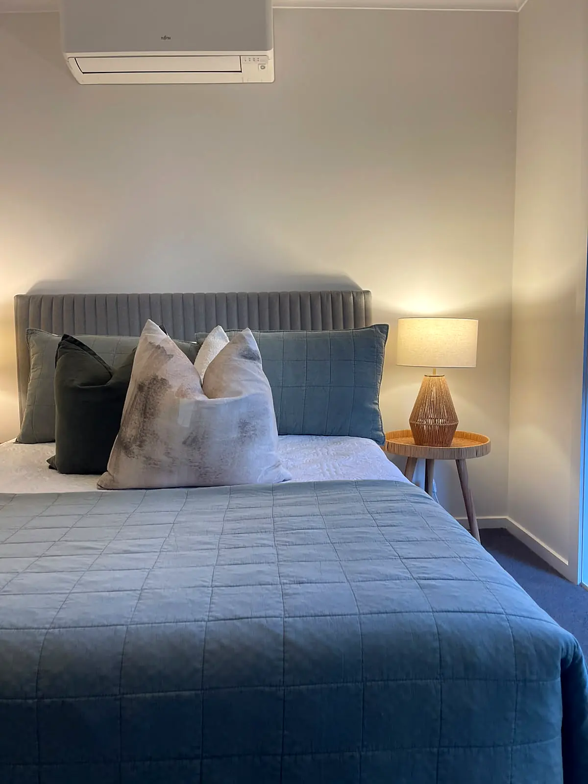 Bedroom staged with ribbed bedhead and soft blue quilt in an Eltham unit