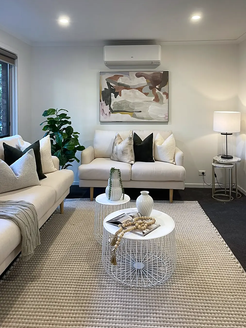 Living room staged with two cream sofas and white coffee tables in an Eltham unit