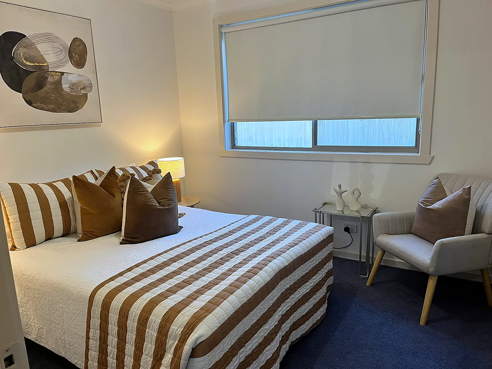 Main bedroom staged with striped linen and armchair in an Epping home