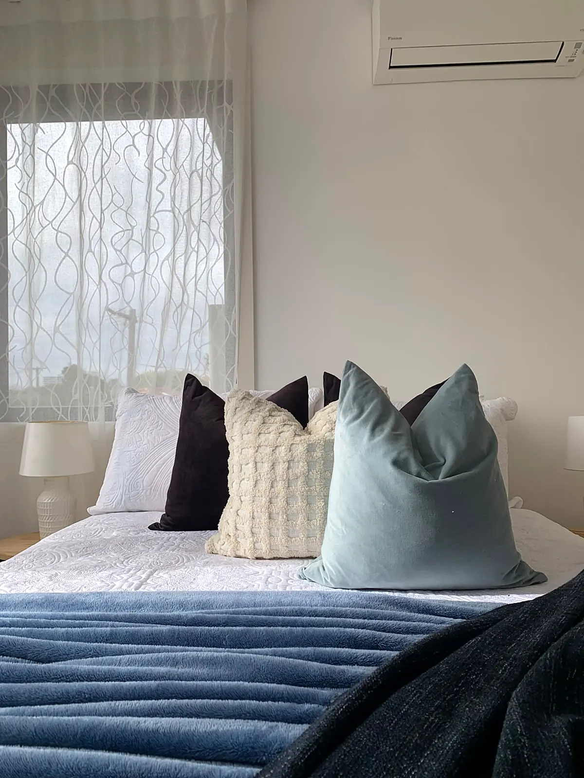 Bedroom staged with blue quilt and layered cushions in a Footscray townhouse