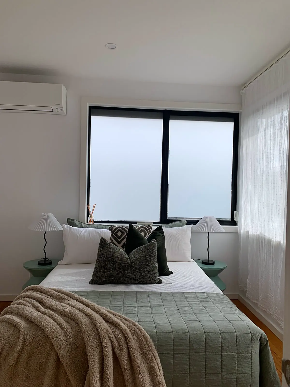 Bedroom staged with sage green quilt and lamps in a Footscray townhouse