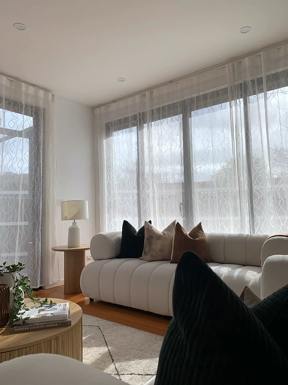 Cream sofa beside full-height windows with sheer curtains in a staged Footscray townhouse