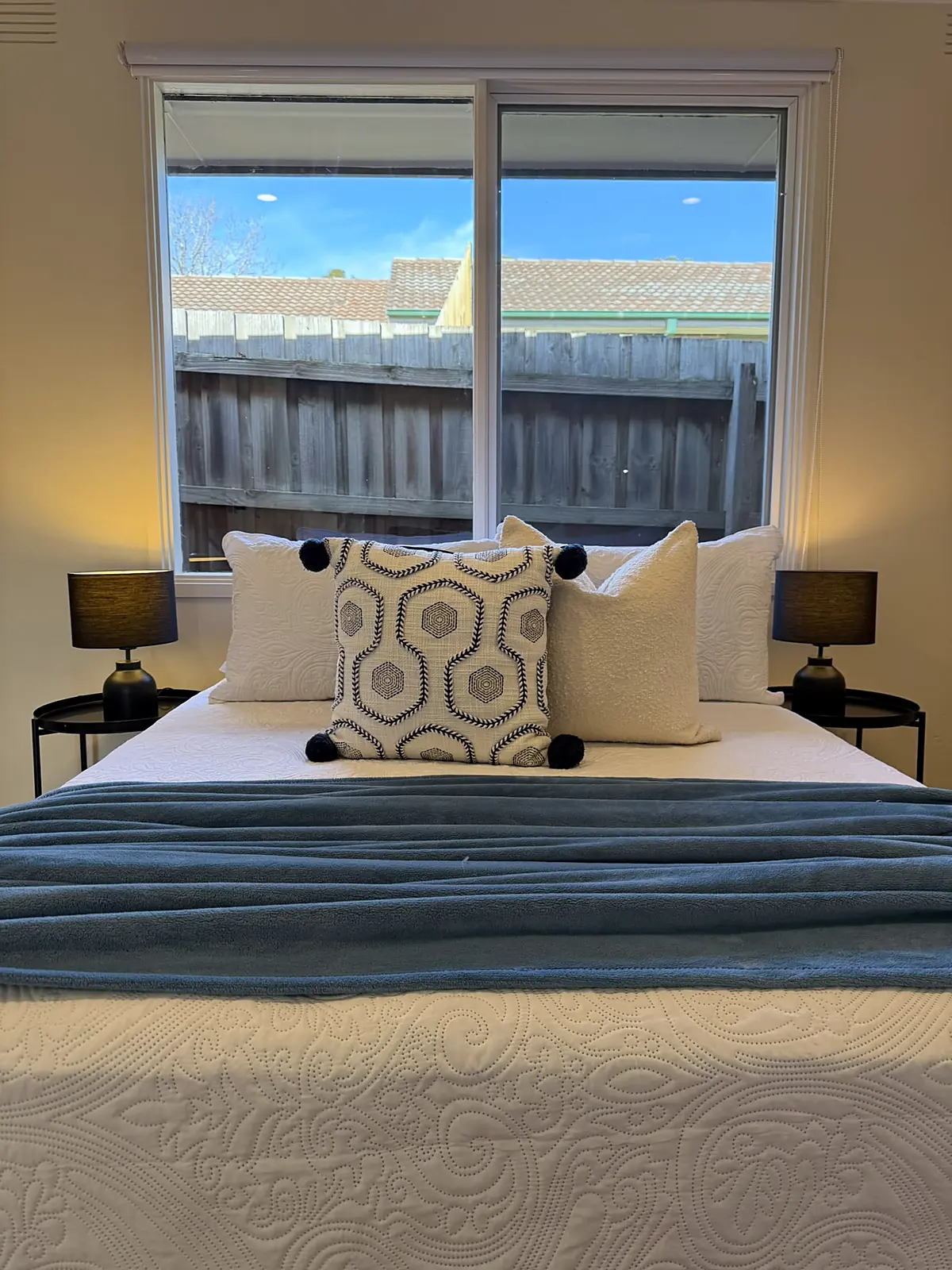 Bedroom staged with blue throw and patterned cushions in a Frankston home