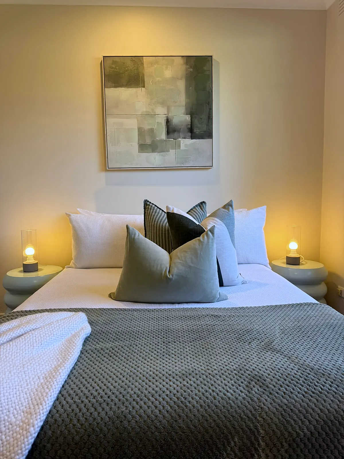 Bedroom styled with green cushions and warm lamps in a Frankston home