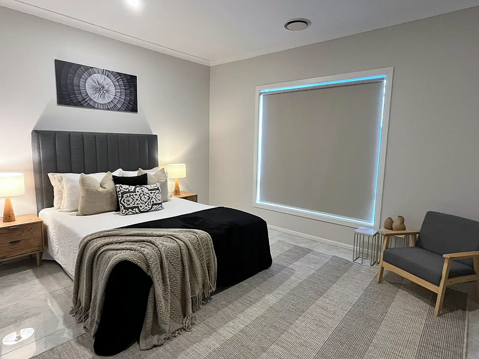 Main bedroom staged with dark bedhead and armchair in a Fraser Rise home