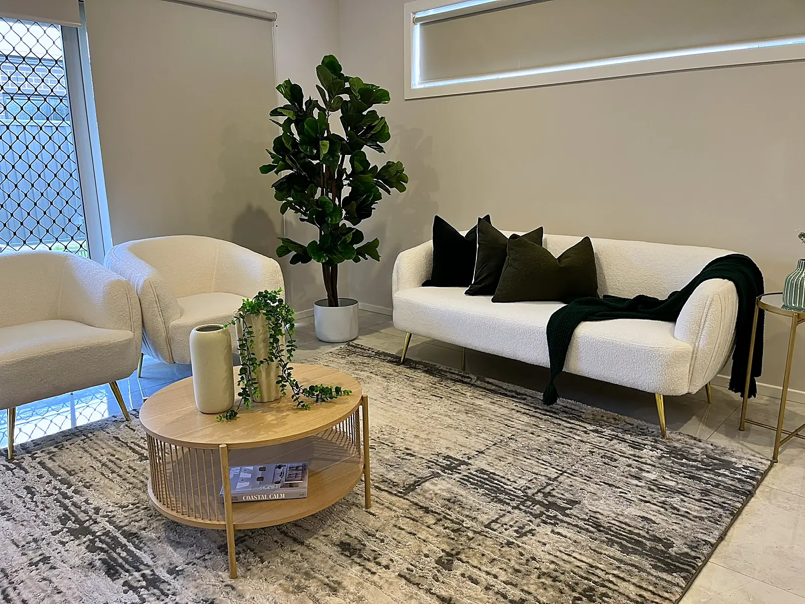 Second living area styled with white sofa and round timber table in a Fraser Rise home