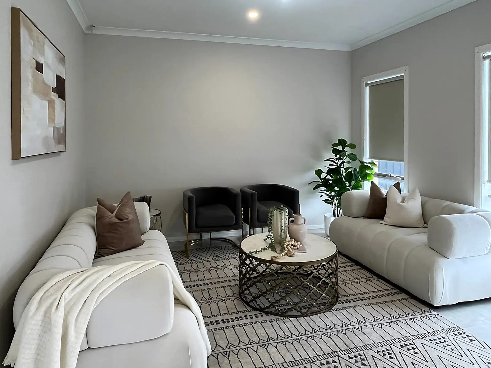 Living room staged with cream sofas and patterned rug in a Fraser Rise home