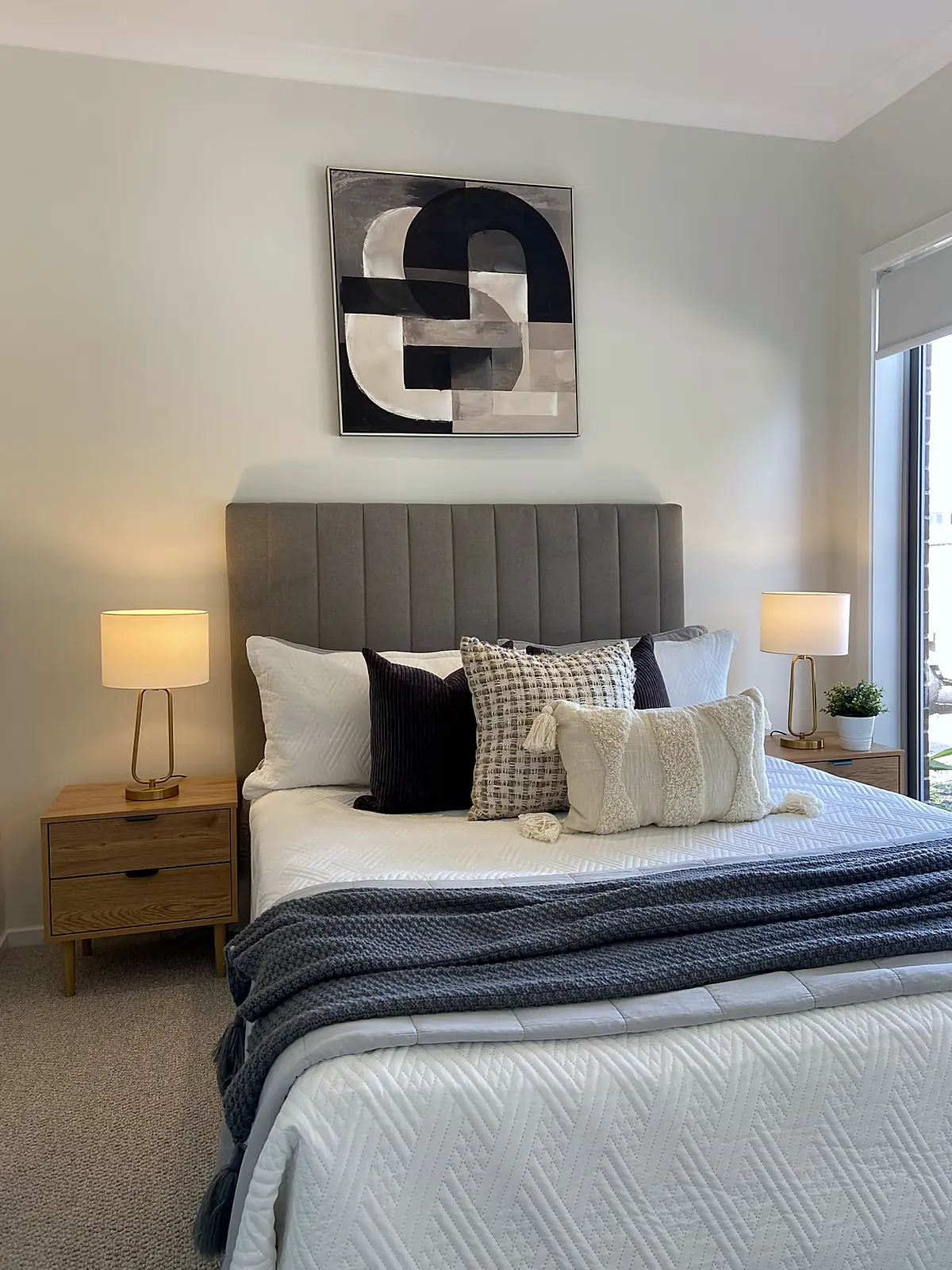 Main bedroom staged with grey bedhead and navy throw in a Harkness home