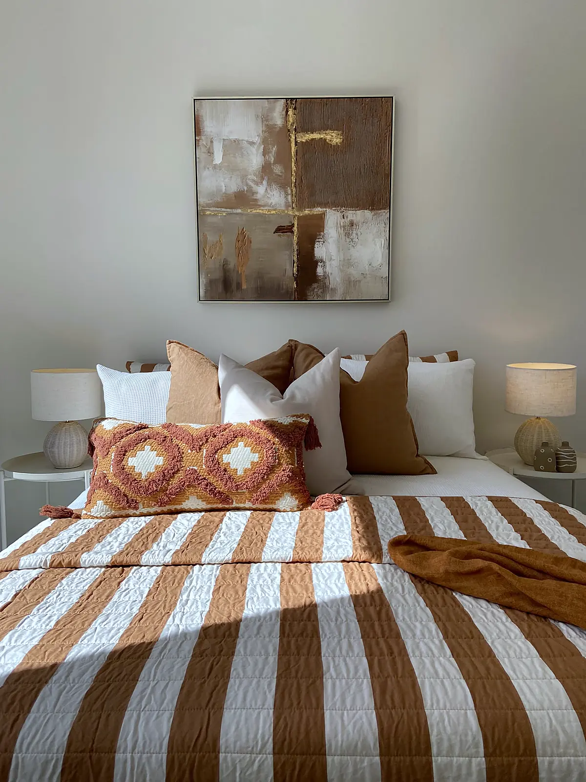 Bedroom styled with rust striped quilt and patterned cushion in a Harkness home