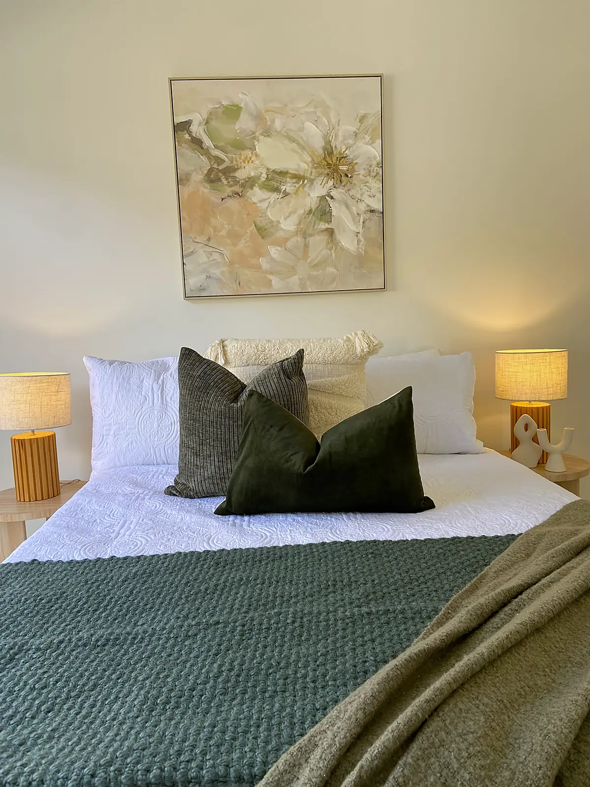 Bedroom staged with forest green quilt and floral artwork in a Harkness home