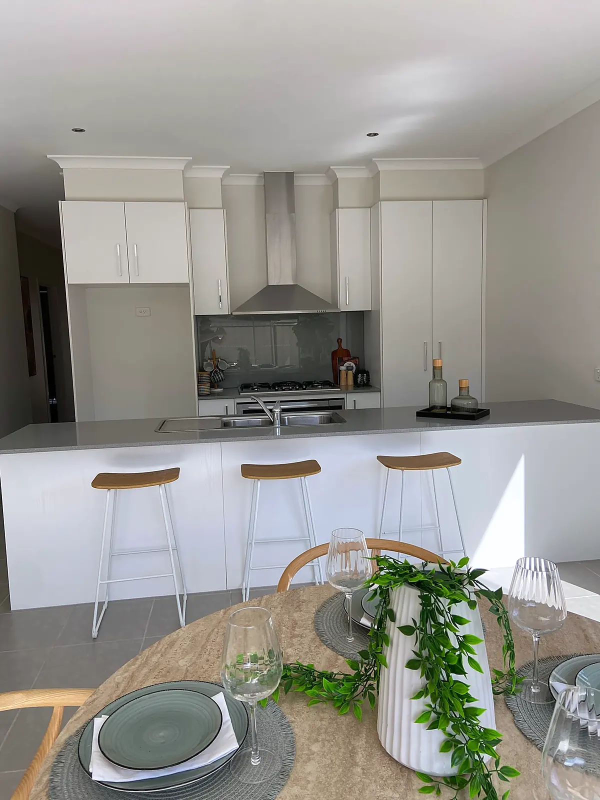 White kitchen with island bench and stools in a staged Harkness home