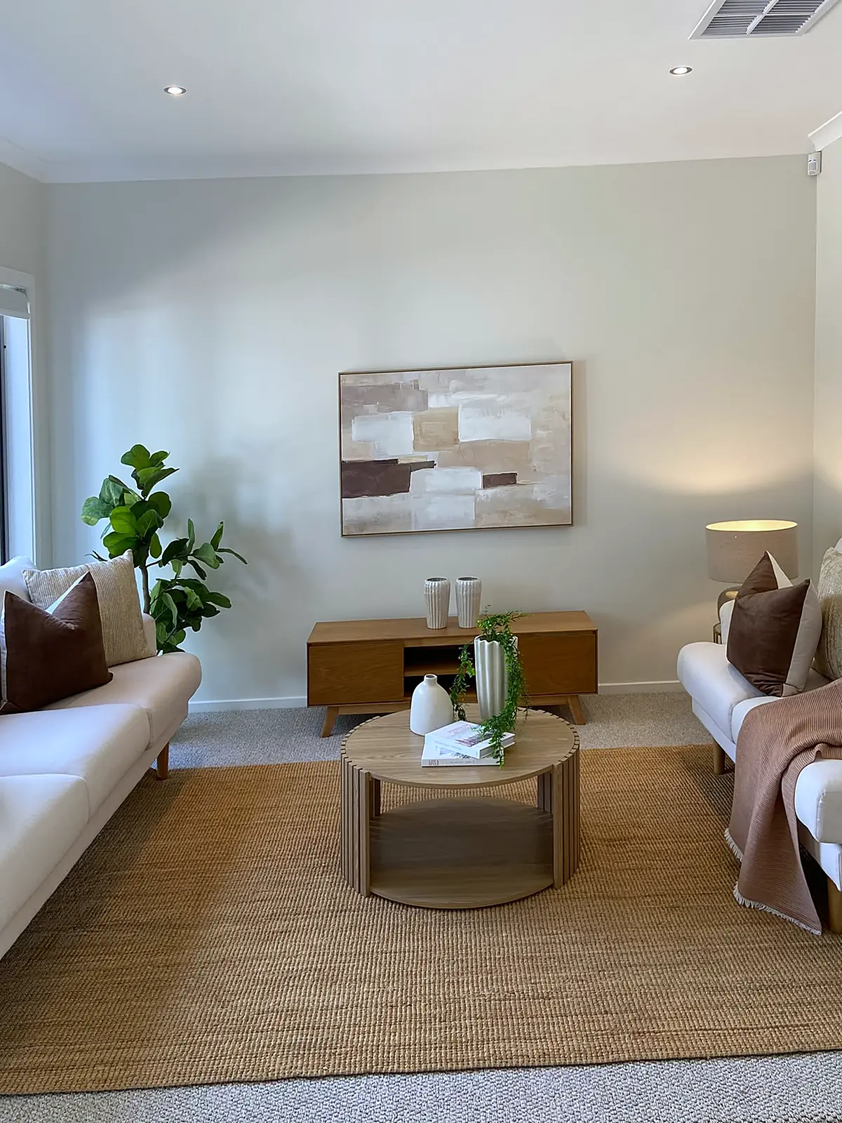 Living room staged with two cream sofas and jute rug in a new Harkness home