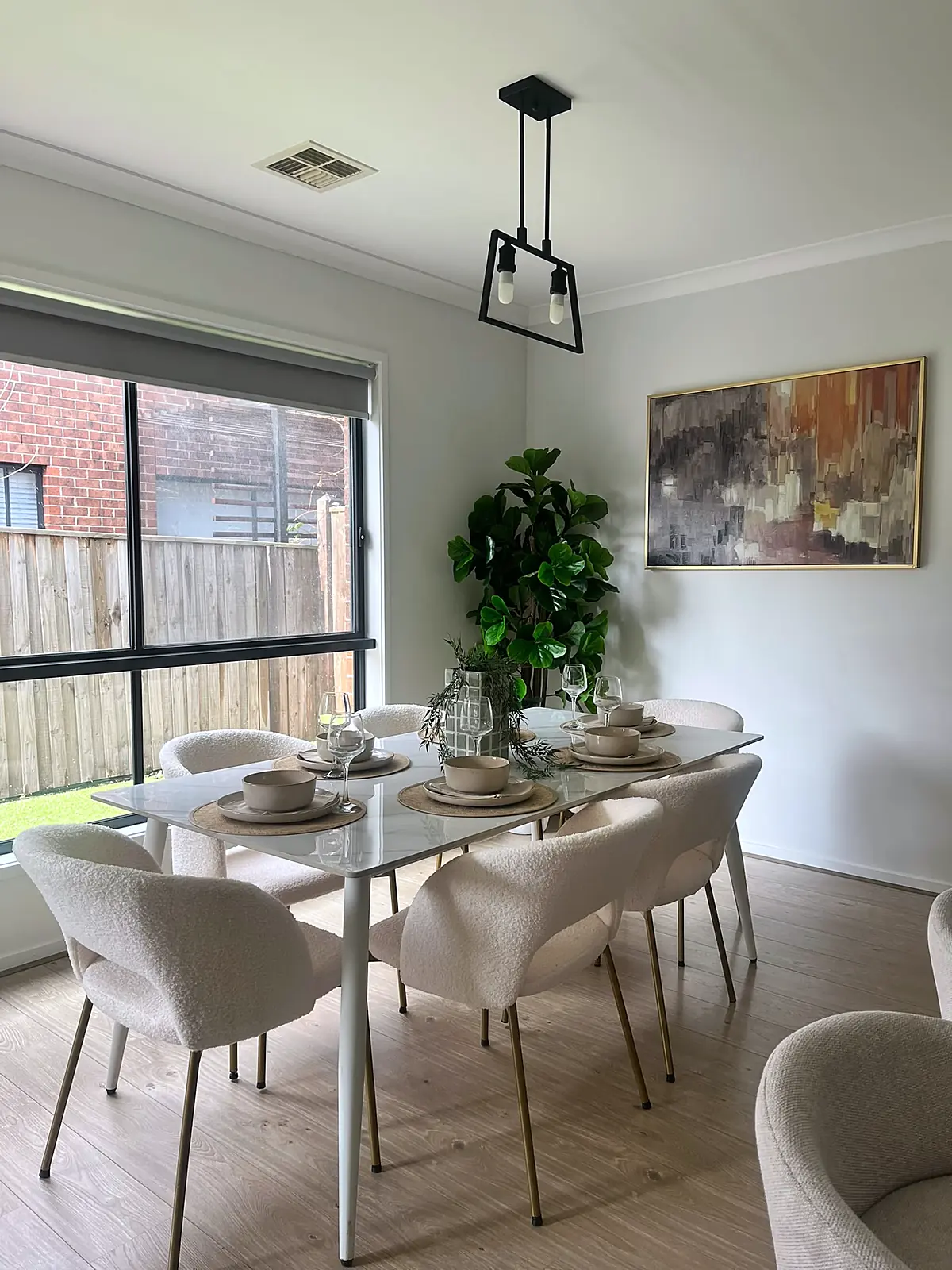 White dining table with curved chairs under a pendant light in a staged Hillside home