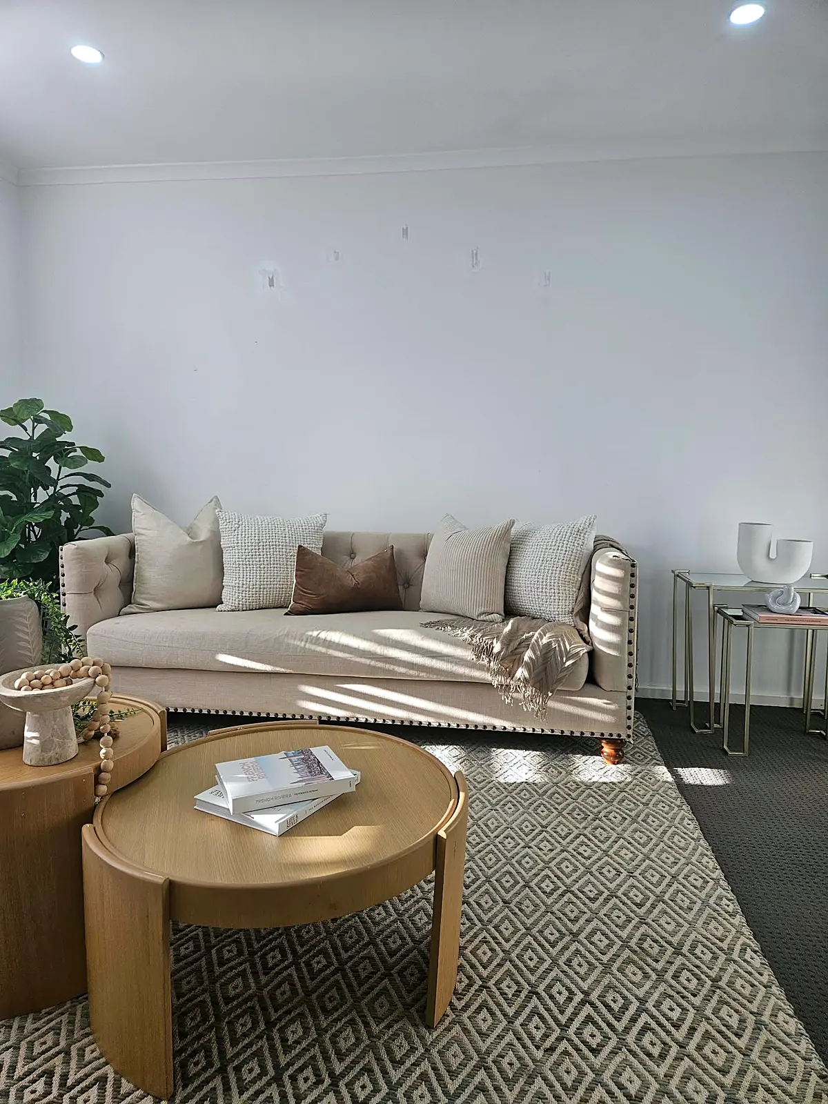 Staged lounge with tufted sofa and round timber coffee tables in a Hoppers Crossing home
