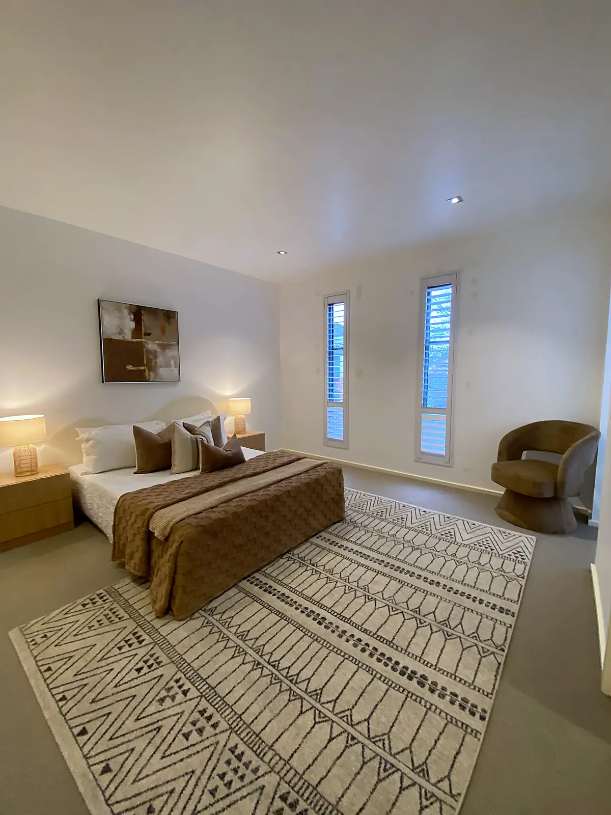 Main bedroom staged with patterned rug and brown linen in a Kew townhouse