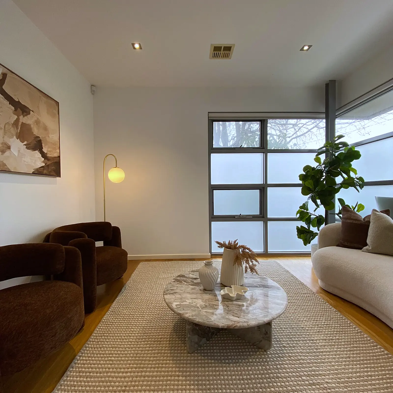 Living room staged with brown armchairs and marble coffee table in a Kew townhouse