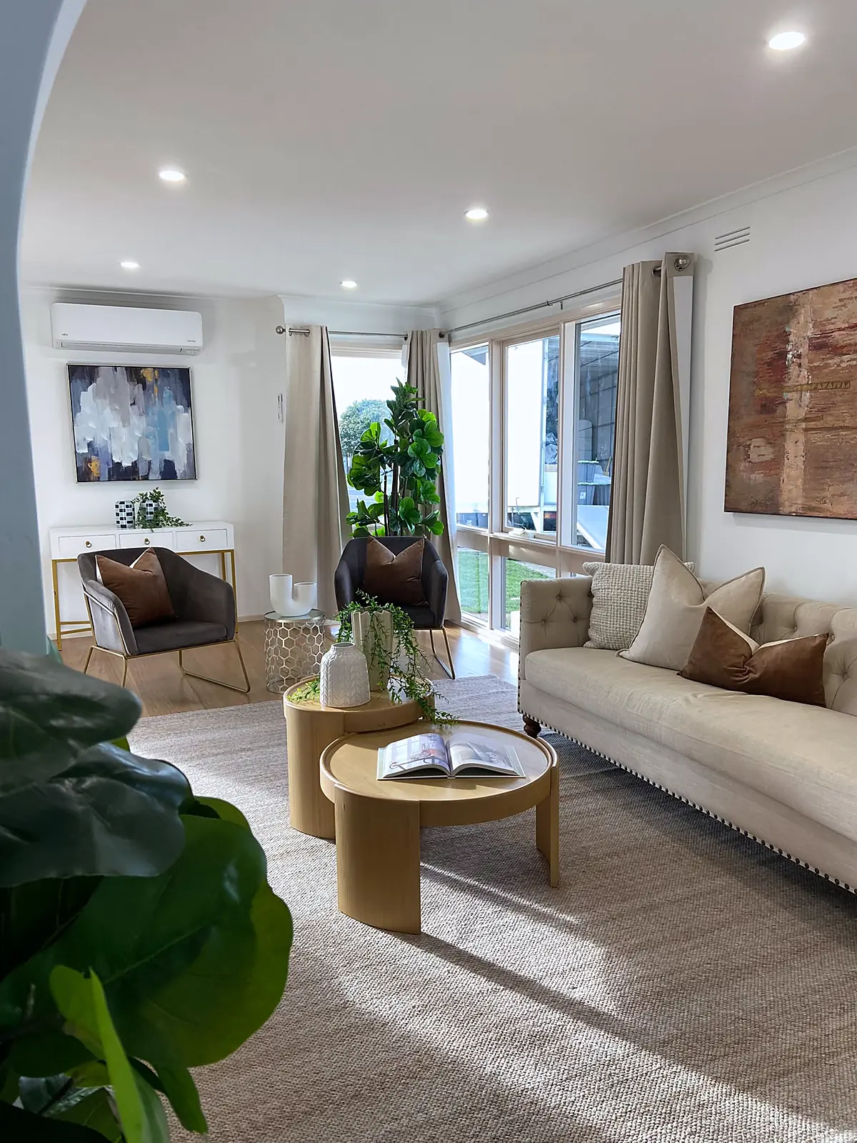Living room staged with cream sofa, armchairs and nesting coffee tables in a Kings Park home